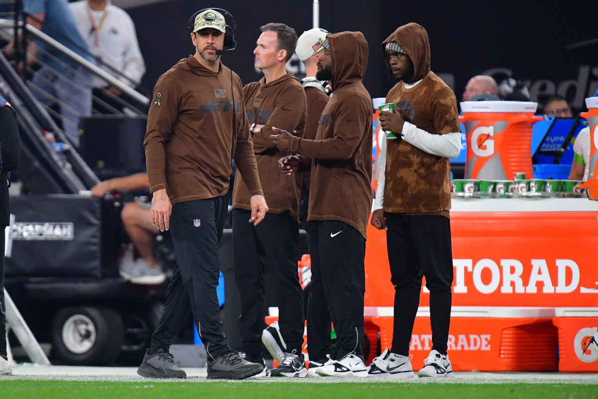 Aaron Rodgers walks along the sideline past a bunch of Jets staff